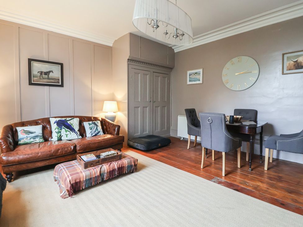 A living room with a leather sofa and dining table at Elstronwick Hall Apartment