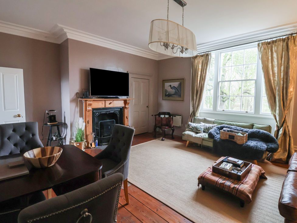 A living room with a television and a fireplace at Elstronwick Hall Apartment