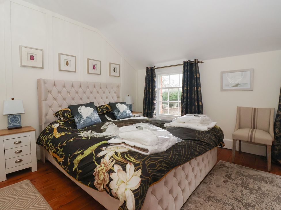 A bedroom with a large bed and bedside table at Elstronwick Hall Apartment