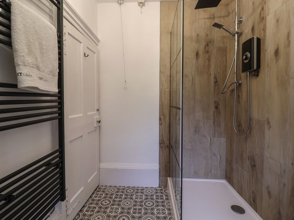 A bathroom with a shower and towel rack at Elstronwick Hall Apartment 