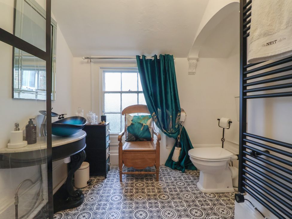 A bathroom with a shower, toilet, washbasin, and curtain at Elstronwick Hall Apartment