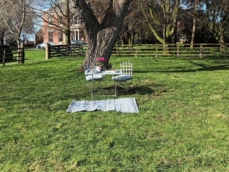 A table and chairs under a tree in a garden at Elstronwick Hall Apartment Elstronwick near Burton Pidsea