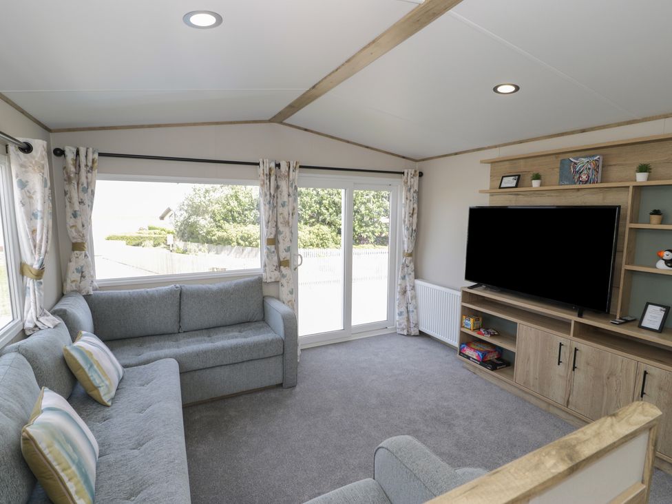 A living room with a sofa and television at Puffin Way Holiday Caravan