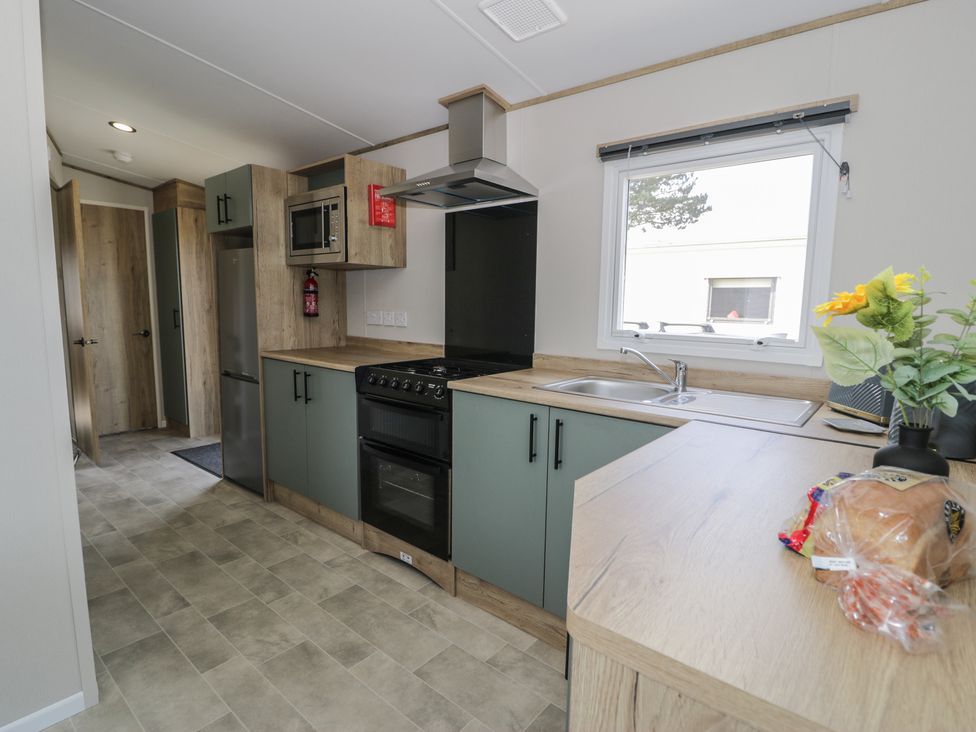 A kitchen with appliances and cabinets at Puffin Way Holiday Caravan 