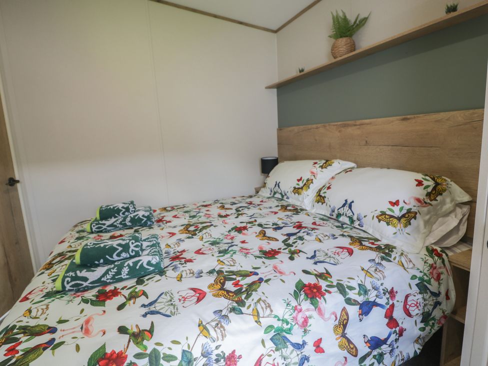 A bedroom with a bed and nightstand at Puffin Way Holiday Caravan