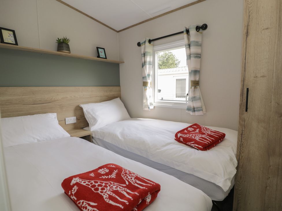 A bedroom with two beds and a window at Puffin Way Holiday Caravan 