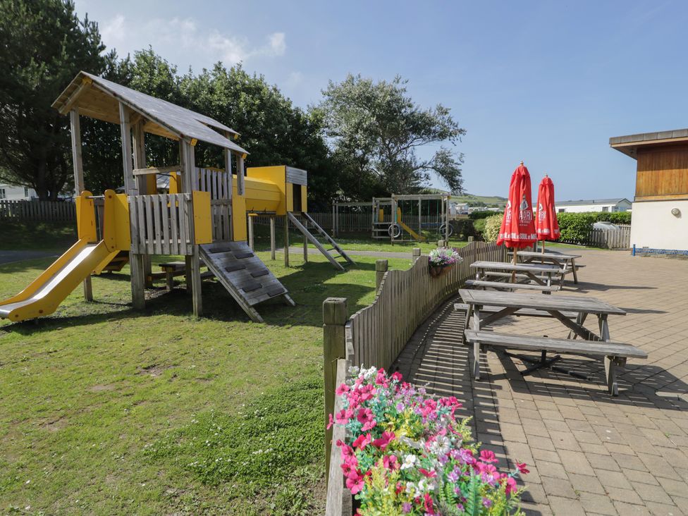 An outdoor play area with a playground and picnic tables at Puffin Way Holiday Caravan 