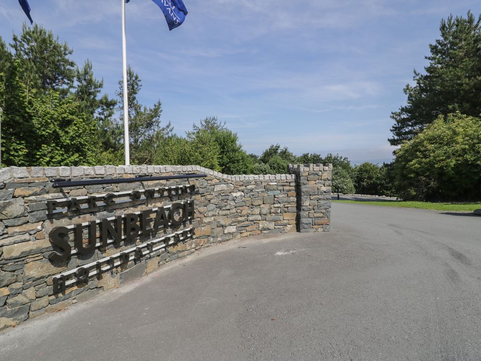 A sign for Sunbeach Holiday Park with trees and road in the background at Puffin Way Holiday Caravan