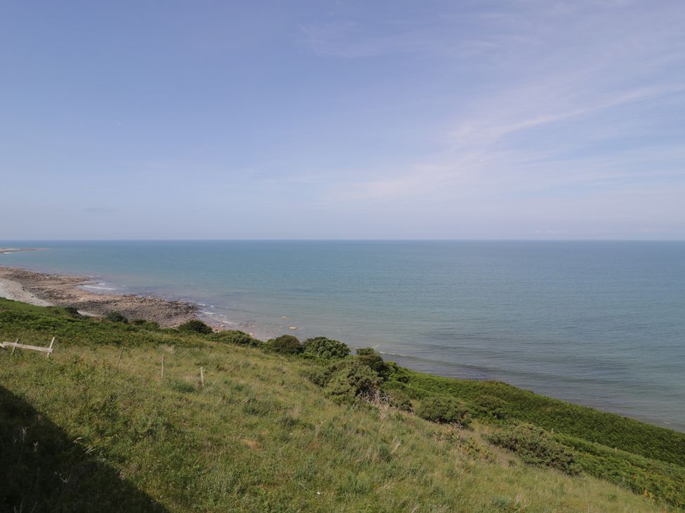 A view of the sea and shoreline with grass and rocks at Puffin Way Holiday Caravan
