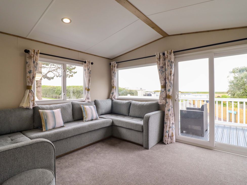 A snug with a gray sofa and windows at 8 Puffin Way Llwyngwril