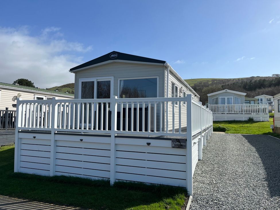 A mobile home with a deck and gravel path at 8 Puffin Way Llwyngwril