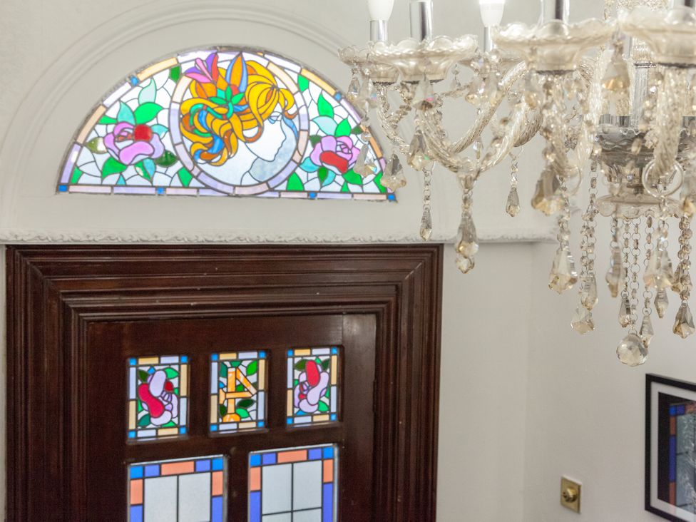 A hallway with a stained glass window and chandelier at 4 Kingscliffe Street Manchester