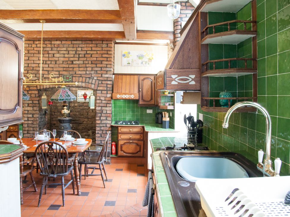 A kitchen with wooden furniture and green tiles at 4 Kingscliffe Street in Manchester