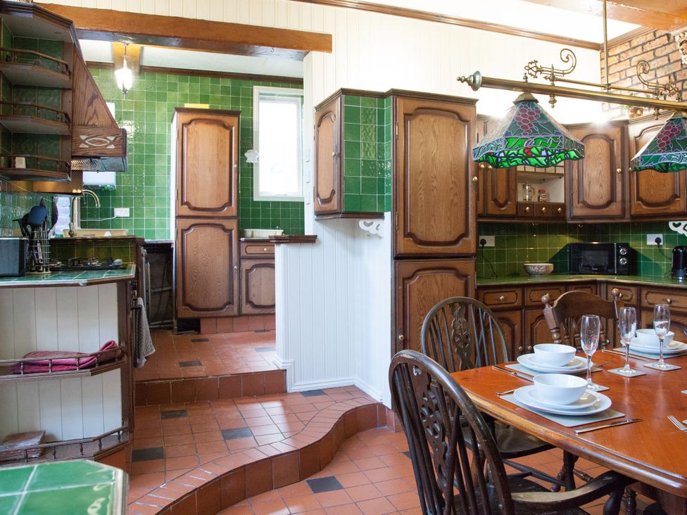 A kitchen with wooden cabinets and a dining table at 4 Kingscliffe Street in Manchester