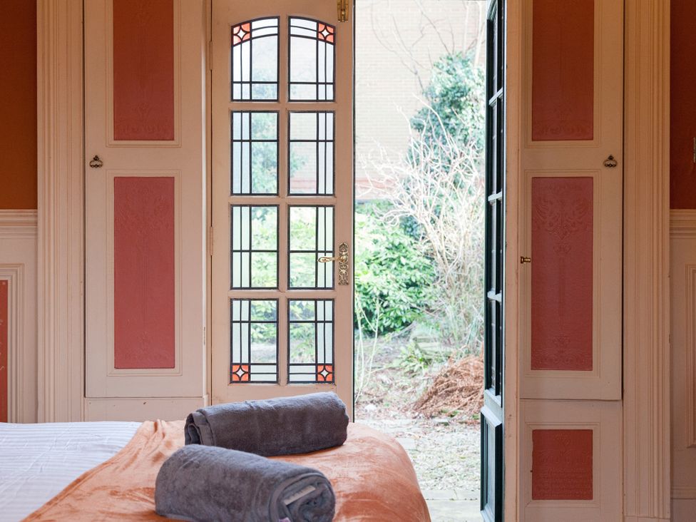 A bedroom with towels on a bed and a door leading to the garden at 4 Kingscliffe Street Manchester