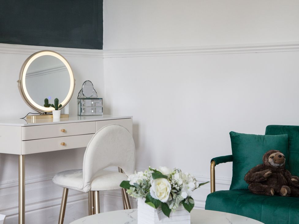 A living room with a vanity desk and sloth stuffed animal at 4 Kingscliffe Street in Manchester