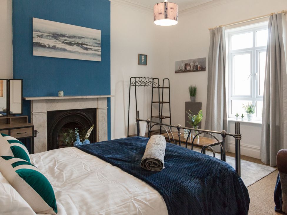 A bedroom with a bed, mirror and fireplace at 4 Kingscliffe Street in Manchester