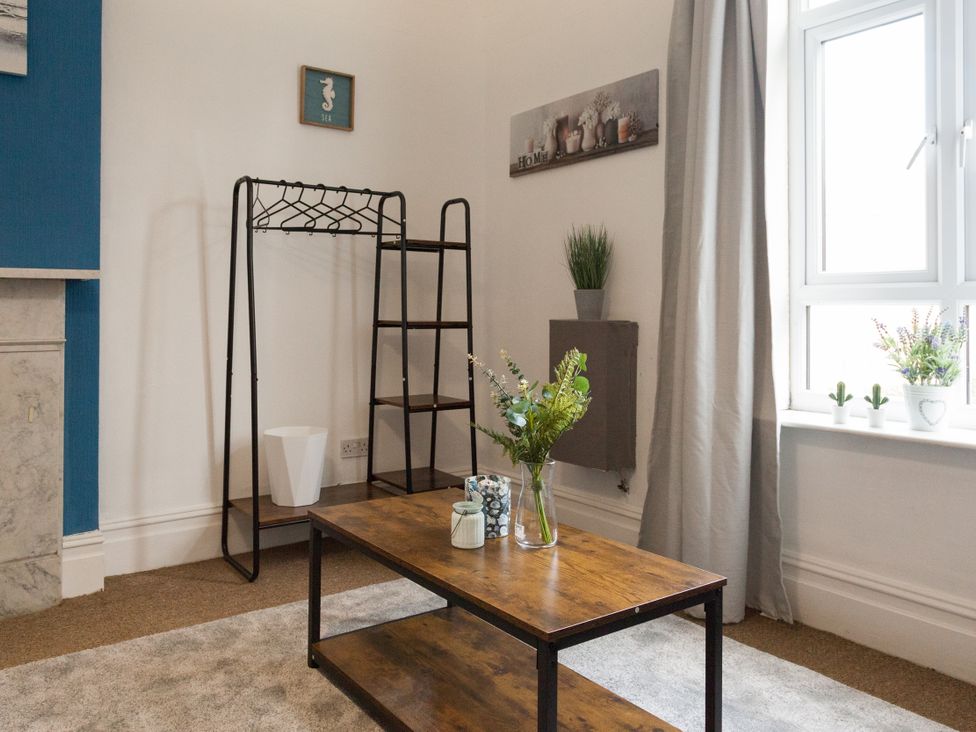 A living room with a table and clothing rack at 4 Kingscliffe Street in Manchester