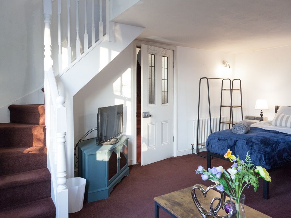A living room with a television and stairs at 4 Kingscliffe Street Manchester