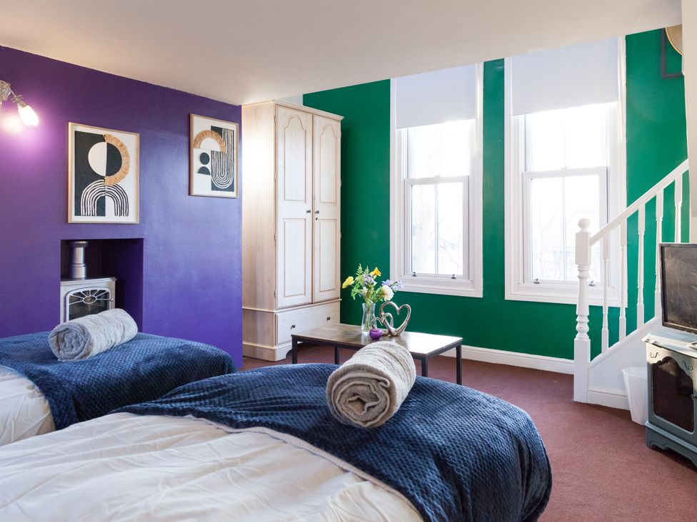 A bedroom with two beds and a cabinet at 4 Kingscliffe Street in Manchester