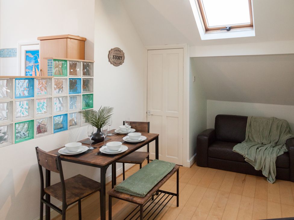 A dining room with a table set for meals and a couch at 4 Kingscliffe Street Manchester