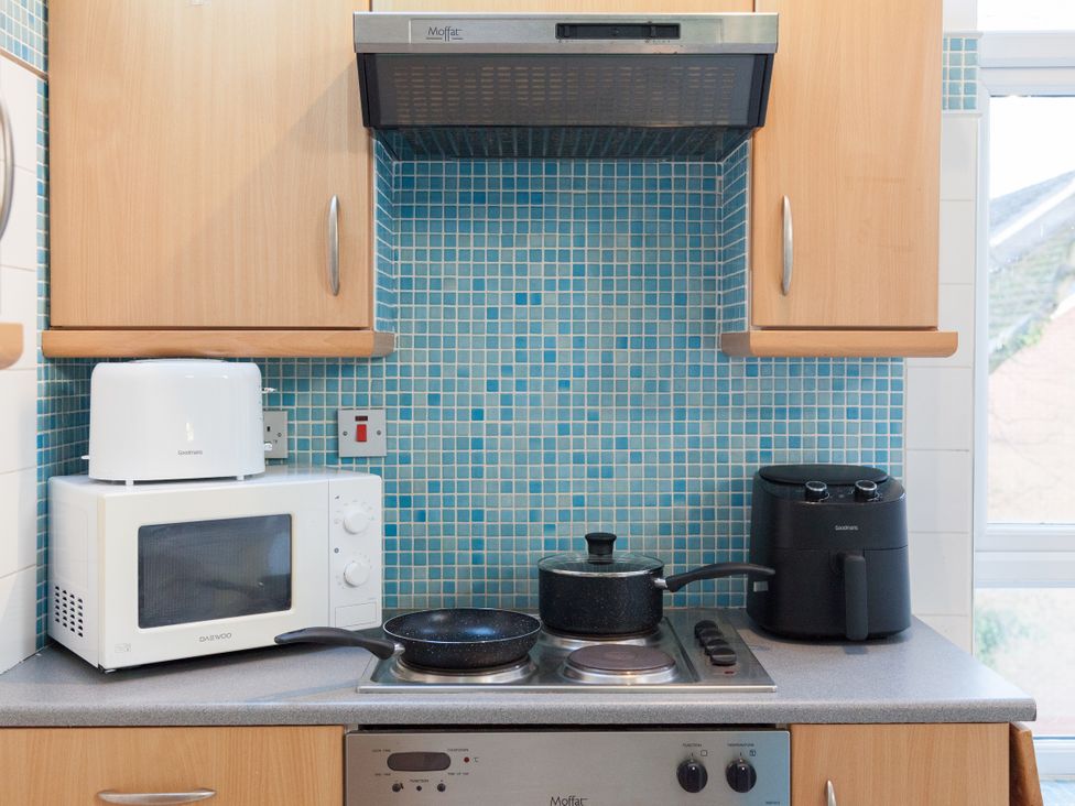A kitchen with a microwave, air fryer and cooker at 4 Kingscliffe Street in Manchester