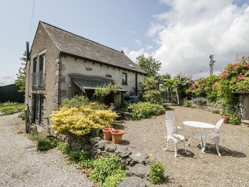 An outdoor area with a house, table, and chairs at Threagill in Carnforth