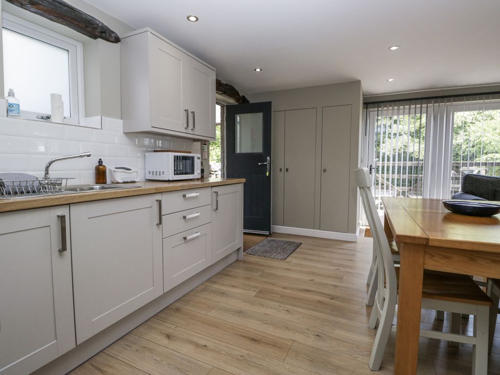 A kitchen with cabinets and a table at Threagill in Carnforth