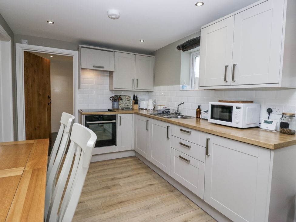 A kitchen with cabinets, sink, microwave and table at Threagill in Carnforth