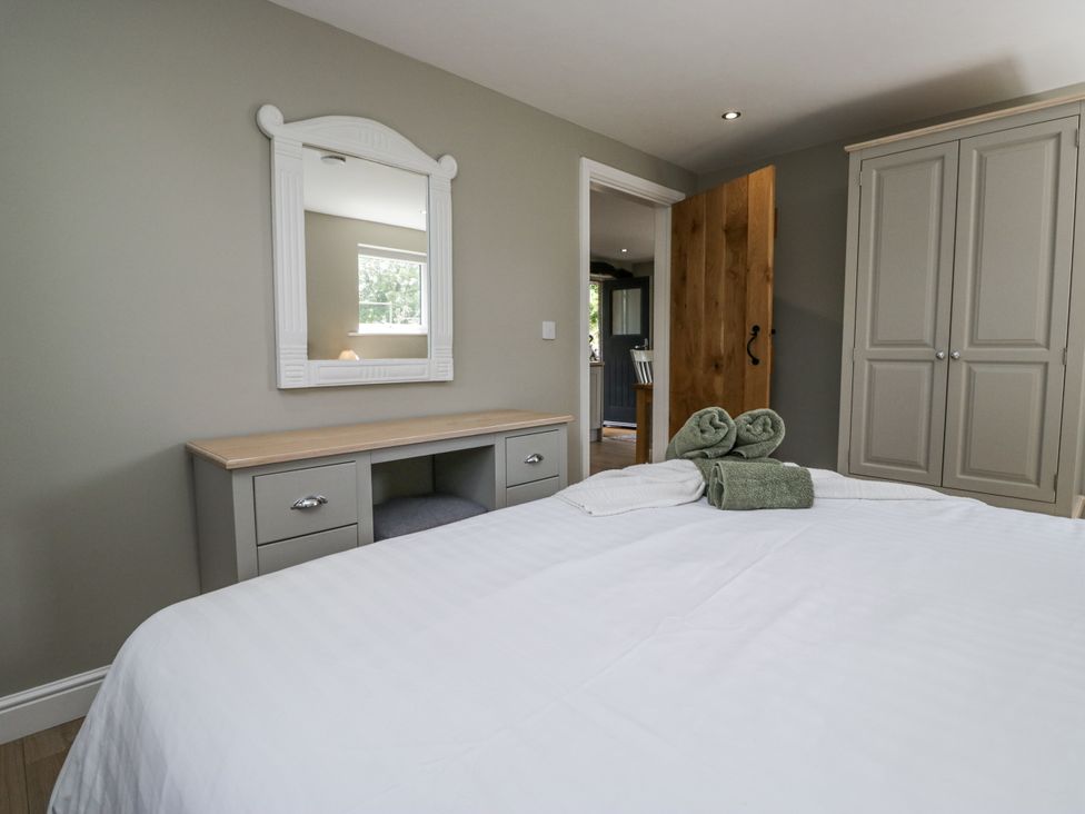 A bedroom with a bed and dressing table at Threagill Carnforth