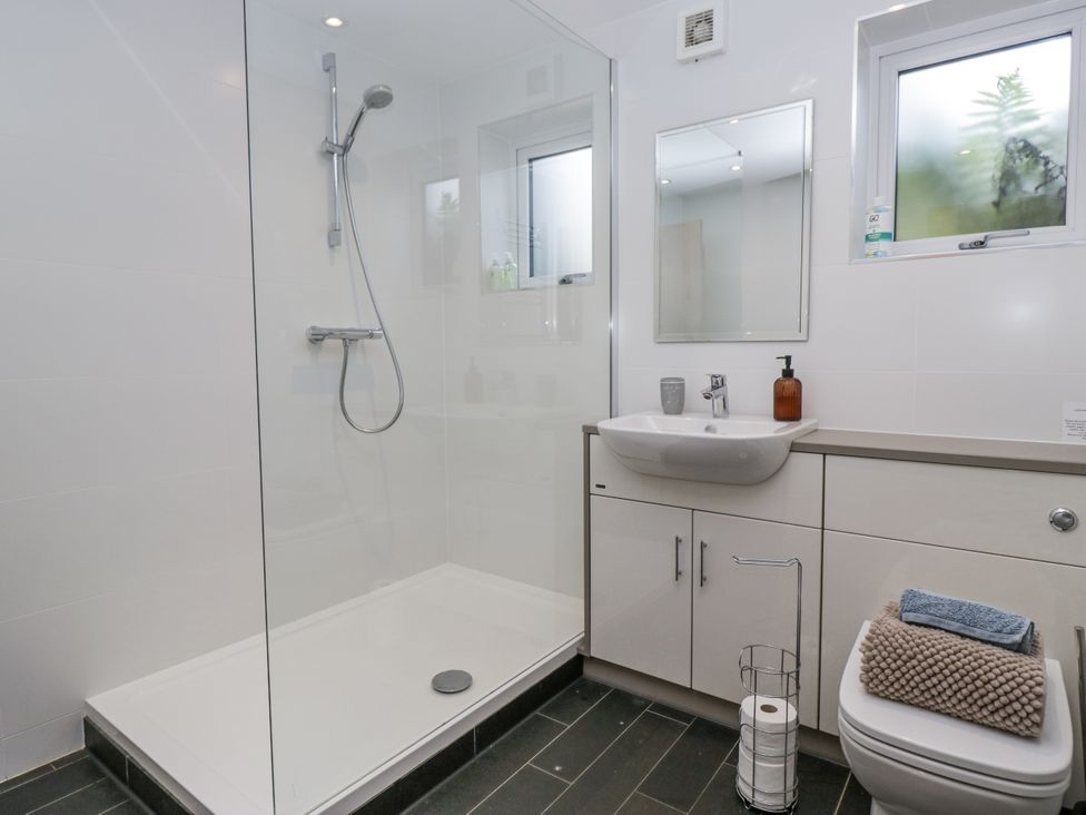 A bathroom with a shower, sink, mirror, and toilet at Threagill in Carnforth