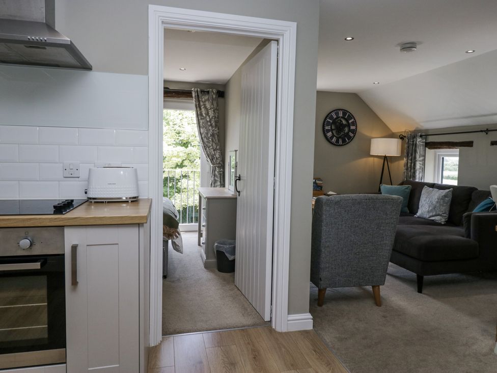 A kitchen with a toaster and stove leading to a living room at Treacle in Carnforth