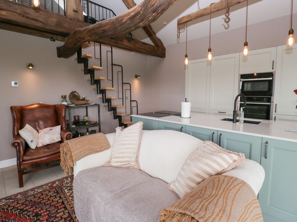 A living room with a staircase and kitchen counter at Lindeth Croft in Carnforth
