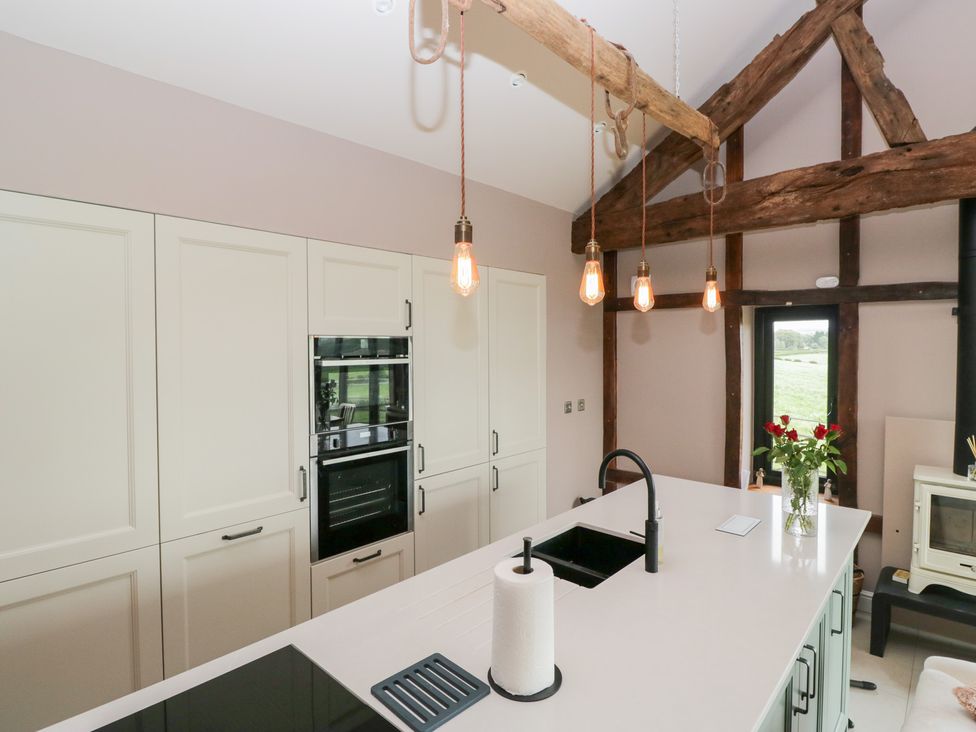 A kitchen with a sink, oven and pendant lights at Lindeth Croft in Carnforth