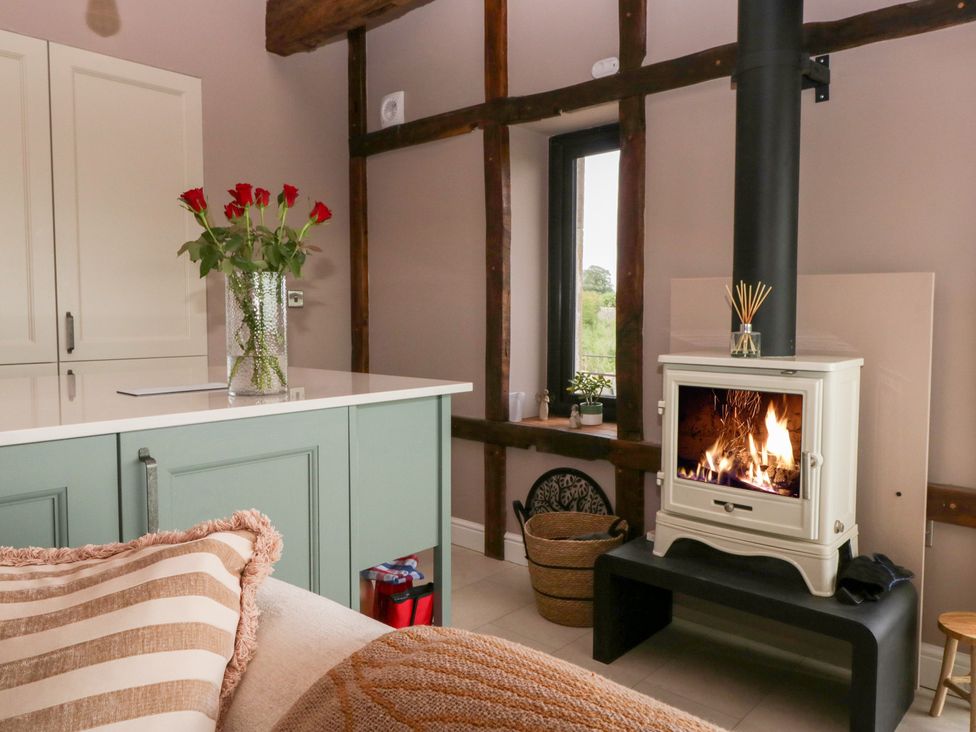 A living room with a fireplace and vase of flowers at Lindeth Croft in Carnforth