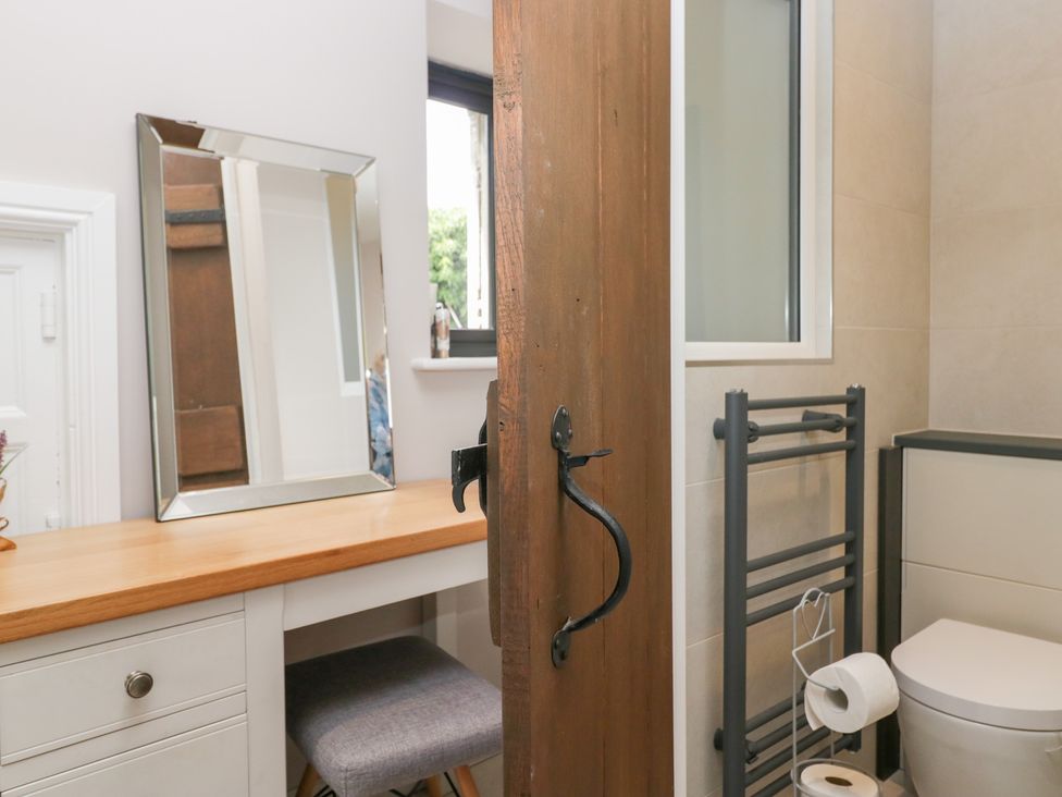 A bathroom with a mirror, table, and towel rail at Lindeth Croft in Carnforth