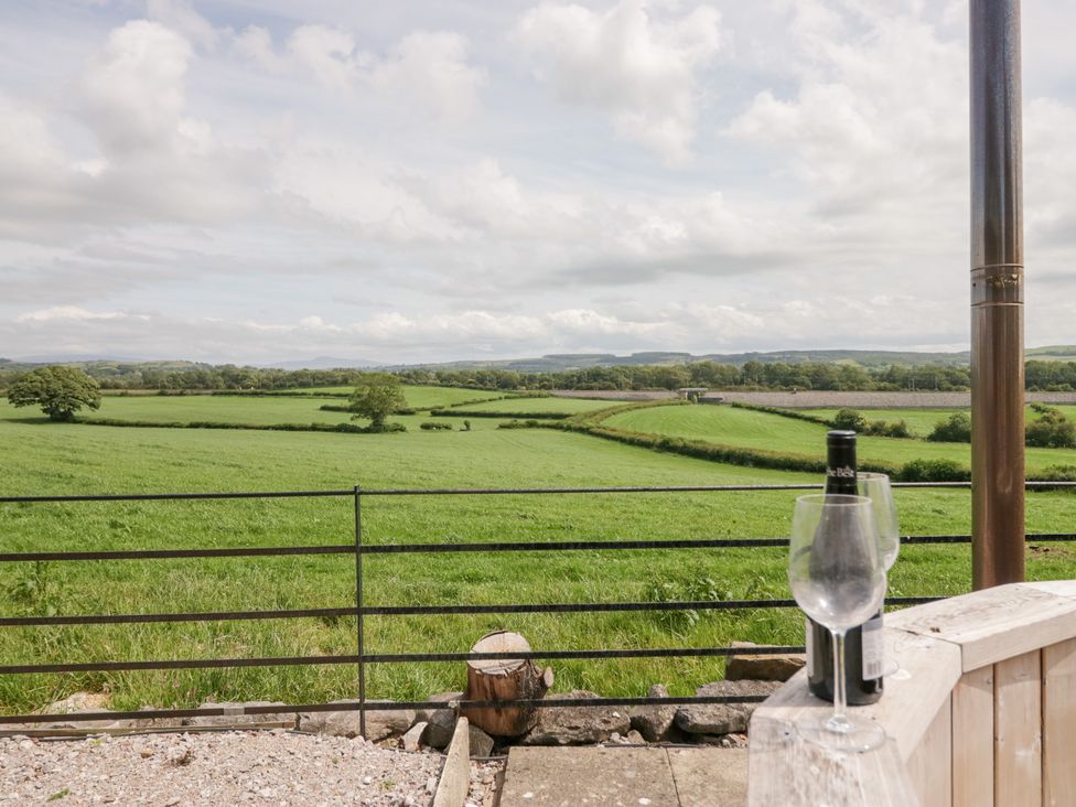 A view of green fields and hills with a glass and bottle at Lindeth Croft in Carnforth