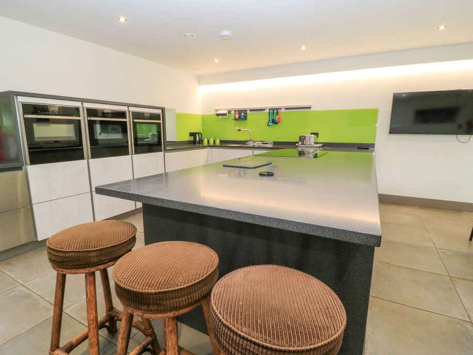 A kitchen with stovetop, stools, ovens and sink at Silver Copse Frilford Heath Near Abingdon