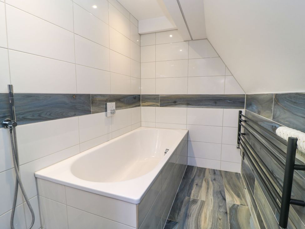 A bathroom with a bathtub and a towel radiator at Silver Copse Frilford Heath Near Abingdon