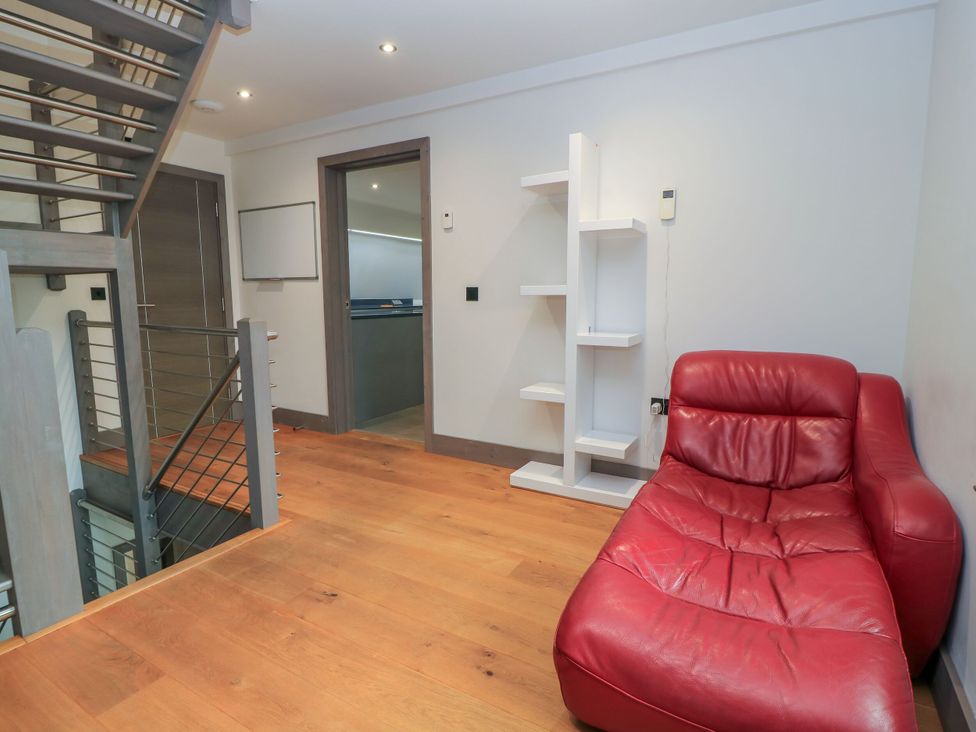 A living room with a red chair and white shelf at Silver Copse in Frilford Heath Near Abingdon