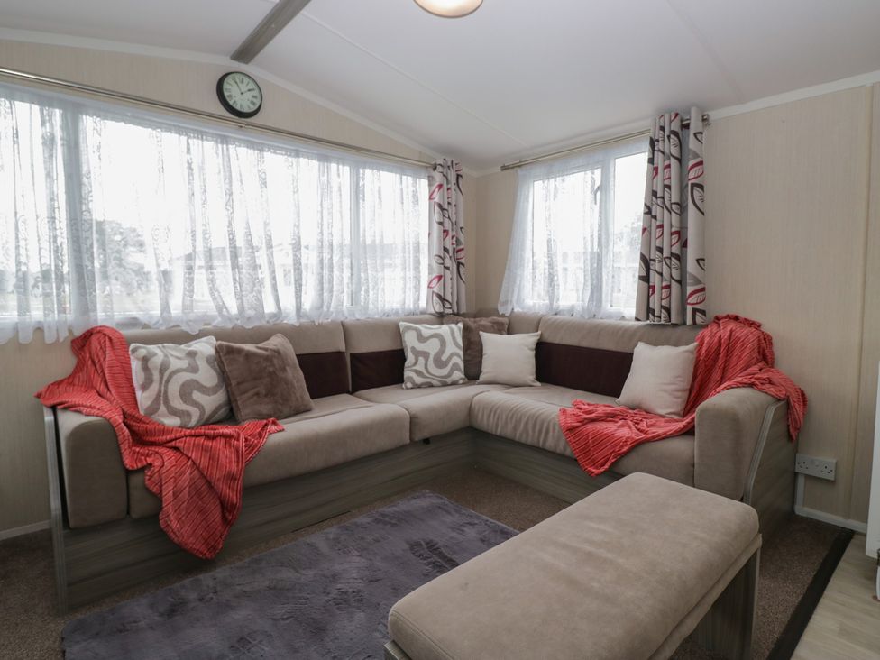 A living room with a sofa, cushions, and a rug at Heathfield Park S4