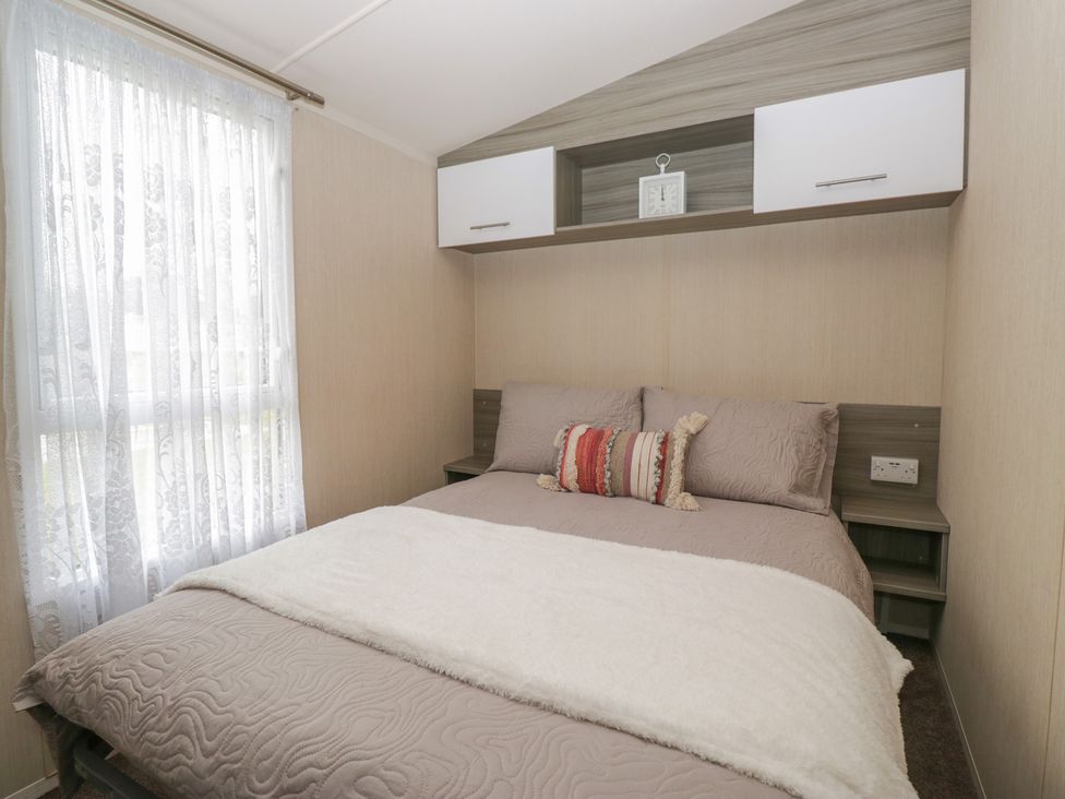A bedroom with a bed and a shelf above at Heathfield Park S4