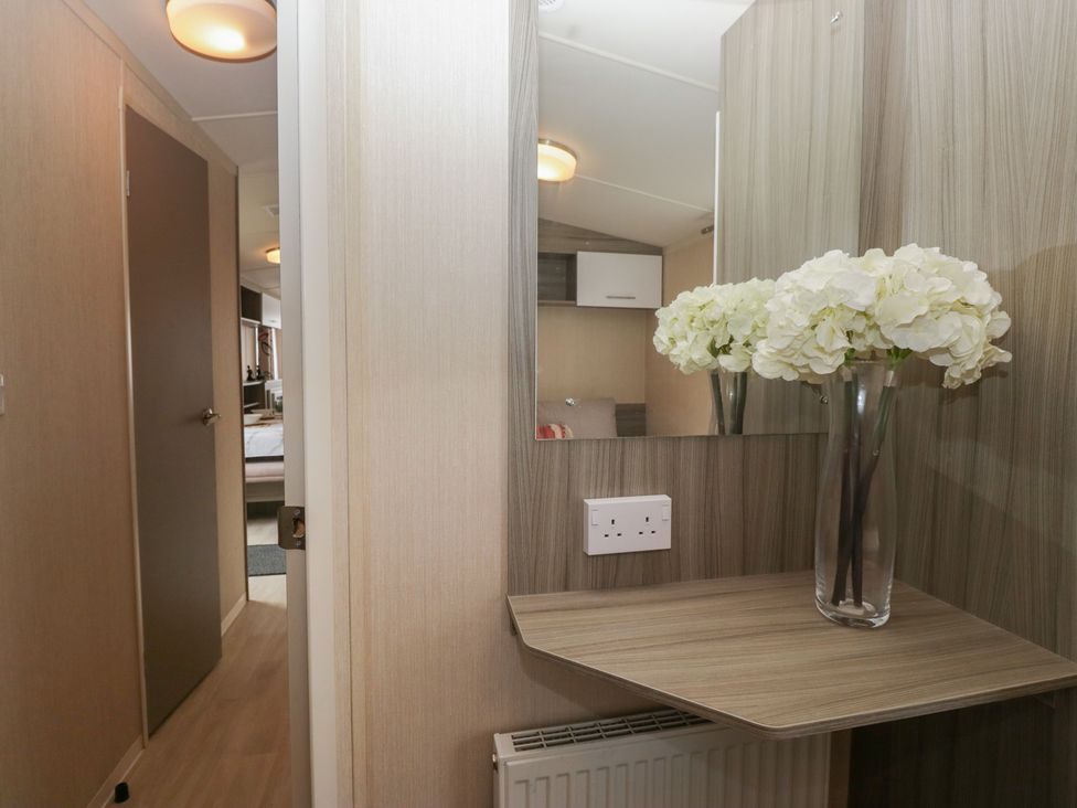 A hallway with a mirror and flowers at Heathfield Park S4