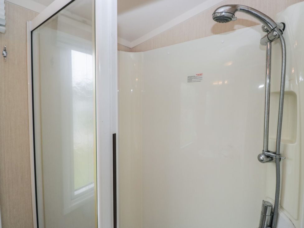 A shower with glass door and showerhead at Heathfield Park S4
