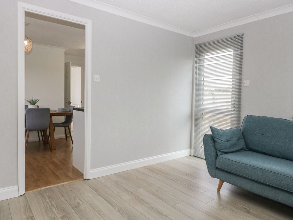 A living room with a sofa and a view into a dining area at Cherry Tree in Kidlington