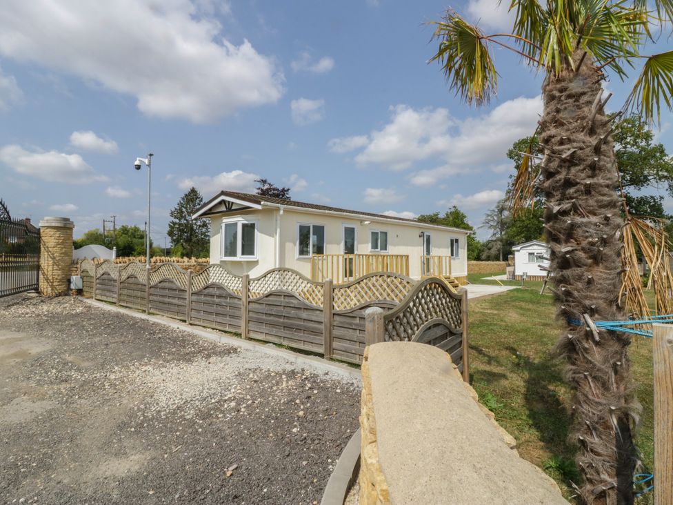A mobile home with a fence and palm tree at Cherry Tree in Kidlington