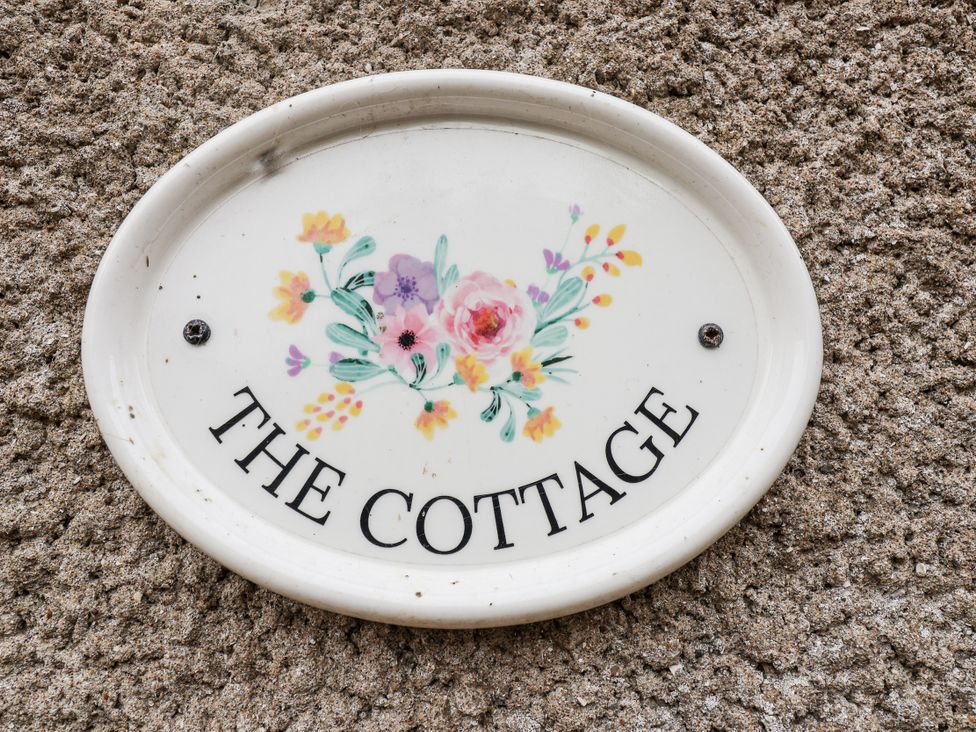 A nameplate with the text 'The Cottage' and floral design at The Cottage Clevedon