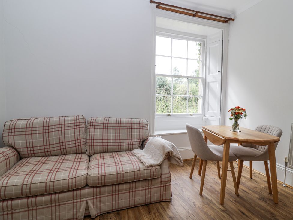 A living room with a sofa and a table with flowers at The Cottage in Clevedon