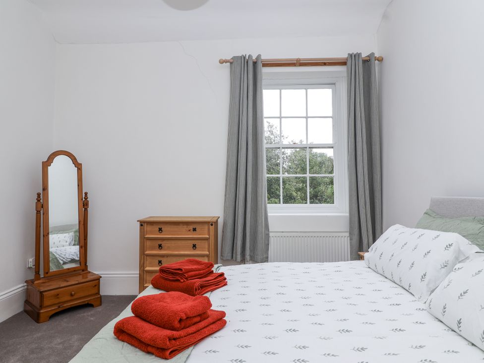 A bedroom with a bed, mirror, and dresser at The Cottage in Clevedon