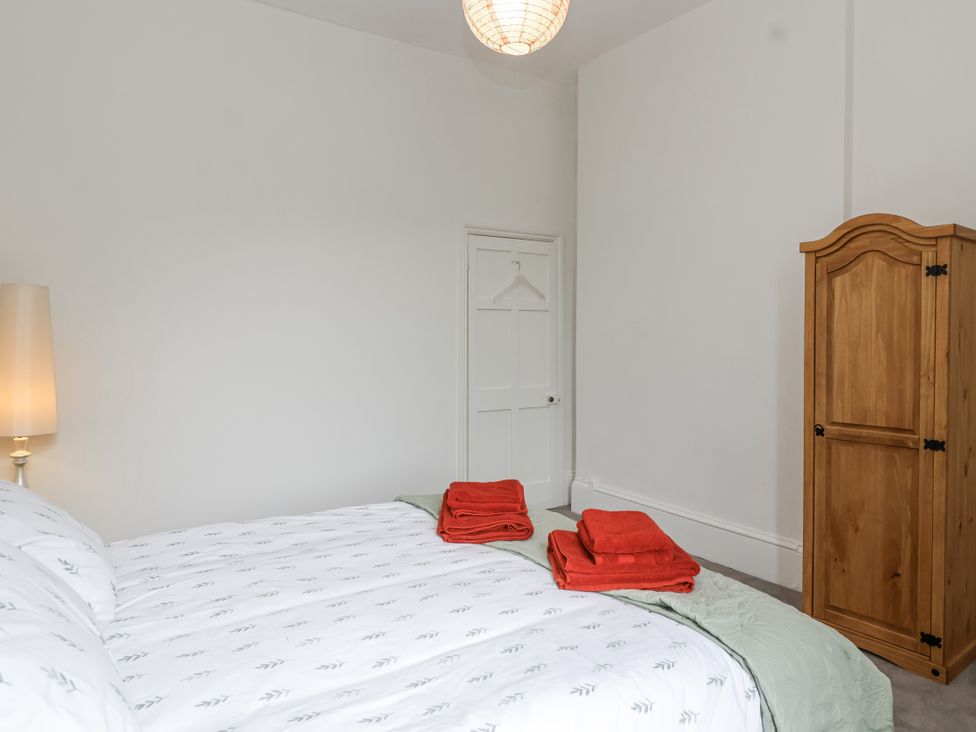 A bedroom with a bed, lamp, towels and wardrobe at The Cottage in Clevedon